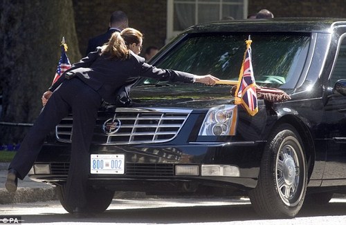 The smartly dressed driver of the President's vehicle  brushes down its shiny exterior as she waits for him outside the Prime  Minister's residence